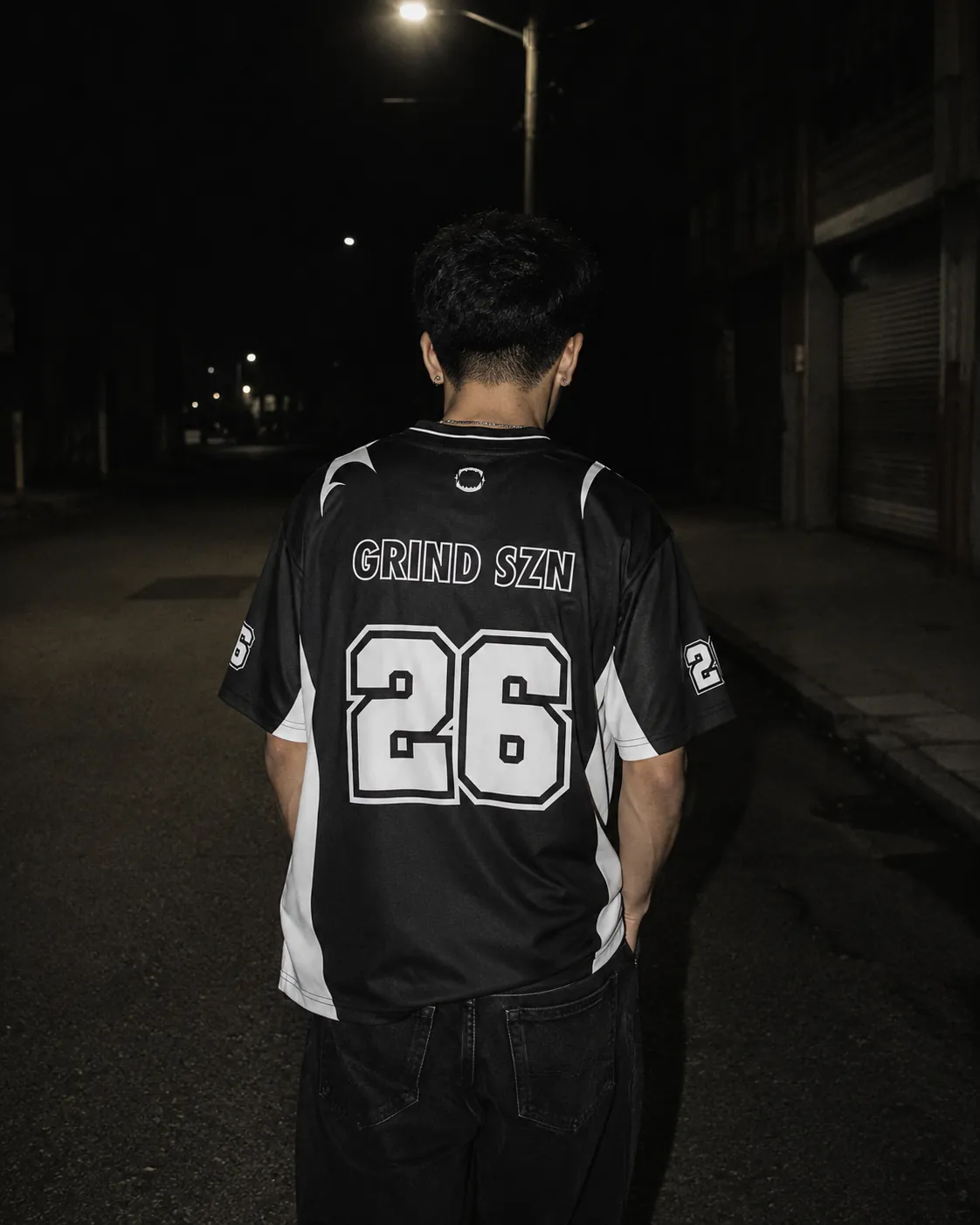 Rider GRINDZ de dos en jersey BLACK OUT GRIND SZN 26 dans une rue de nuit